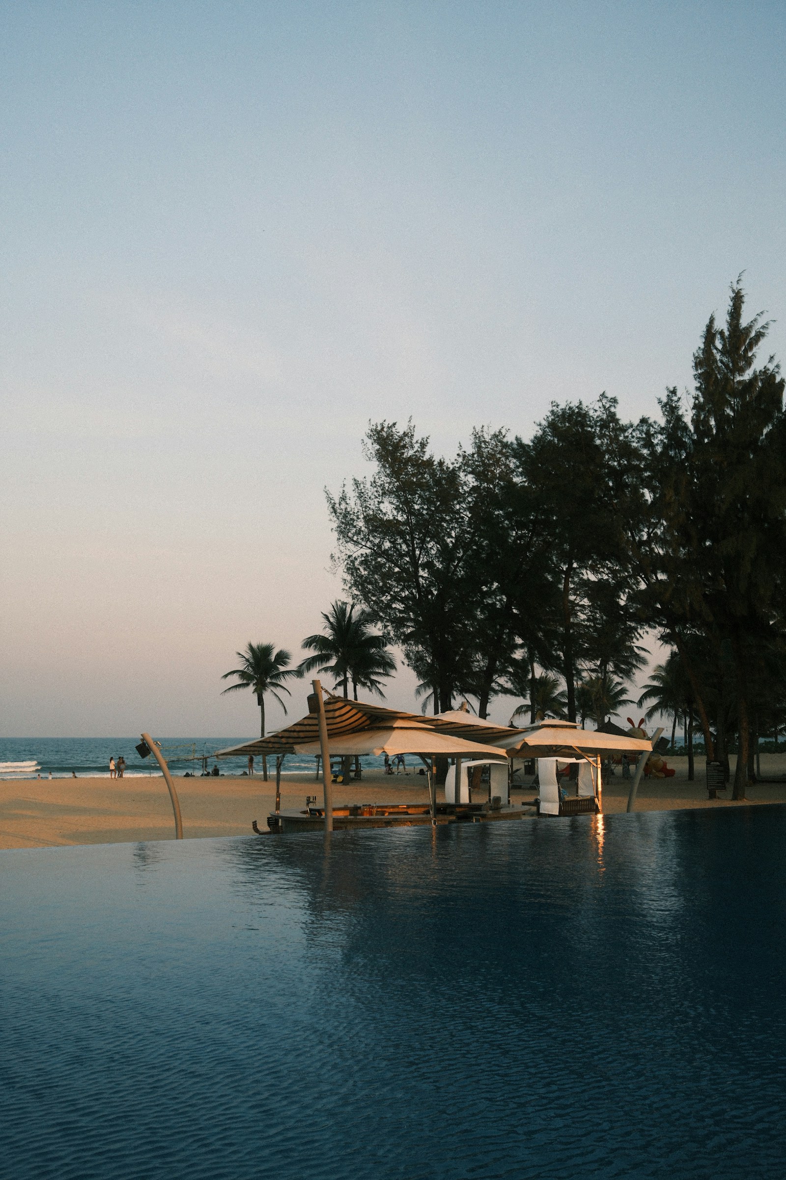 Infinity pool overlooking a tropical beach at sunset